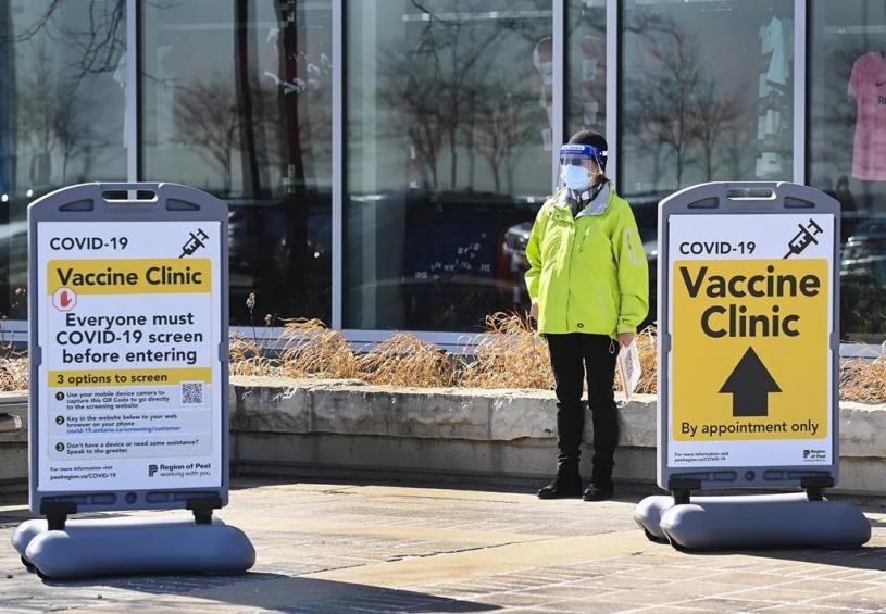 A worker waits to assist people outside at a mass COVID-19 vaccination site during the COVID-19 pandemic in Mississauga, Ont., on Monday, March 22, 2021. THE CANADIAN PRESS/Nathan Denette