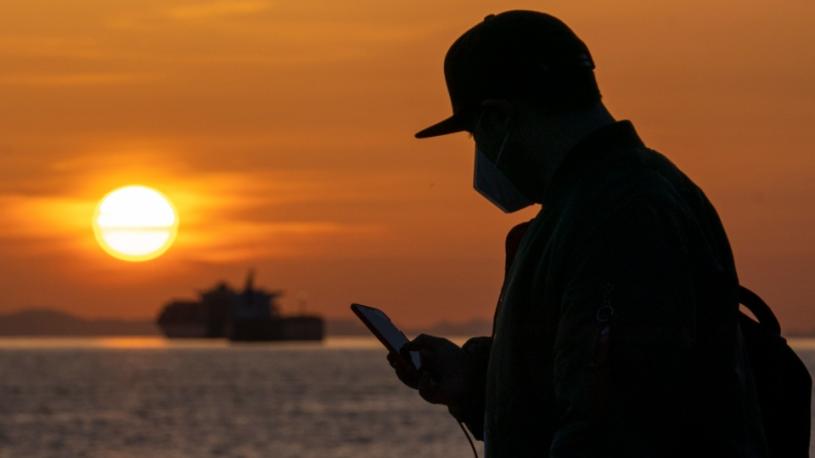 圖為4月5日在英吉利灣（English Bay），一名戴口罩男子在查看他的手機。加通社