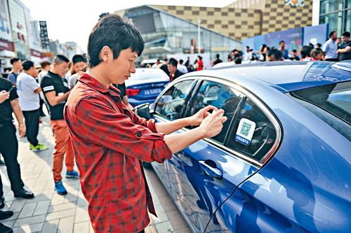 遼寧瀋陽市民在共享汽車前掃描二維碼。中新社