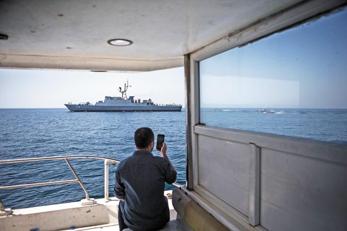 一名男子用手机拍摄在霍尔木兹海峡巡逻的伊朗军舰。新华社