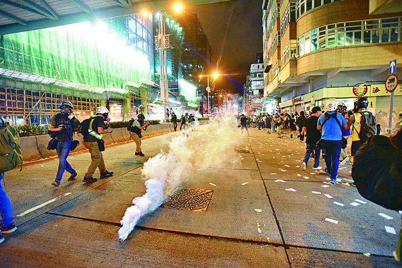 示威者藉燒街衣，在深水埗警署外集結，警放催淚彈驅散
