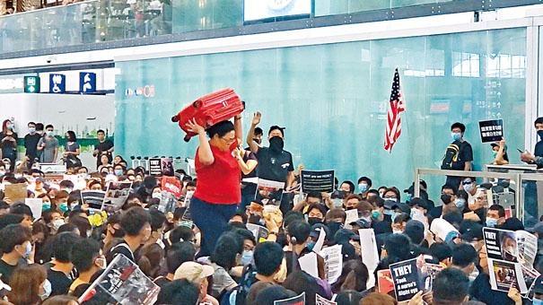 身穿紅衣的星洲婦人手持行李在黑衣示威者中穿插一幕，在網上爆紅。