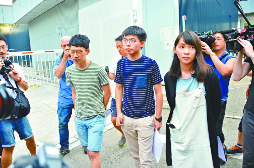 「香港眾志」秘書長黃之鋒（左）及成員周庭（右）30日早上突然被拘捕，並押往灣仔警察總部。資料圖片