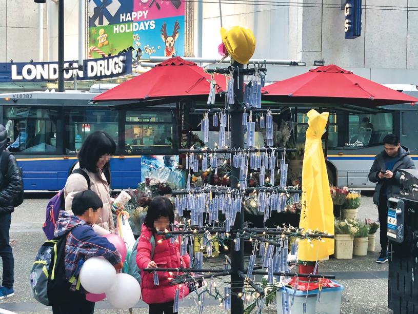 ■民众带同子女在圣诞树上挂上纸质催泪弹模型。
