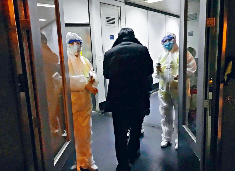 北京机场22日有穿上保护衣的卫生官员在闸口等候检查由武汉入境的旅客。美联社