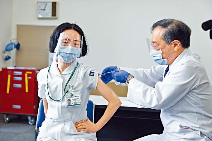 东京医疗中心一名医护周三接受院长亲自注射新冠疫苗。