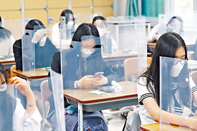 韩国大田市一所中学在书桌架起胶板防疫。
