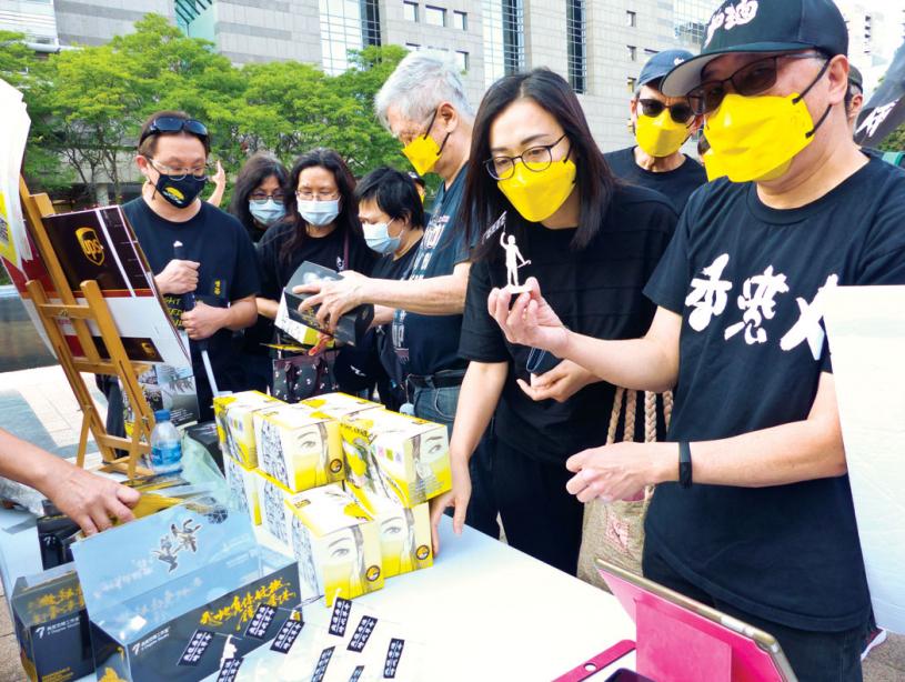 ■多倫多香港家長組發言人謝先生向市民介紹義賣物品。本報記者攝
