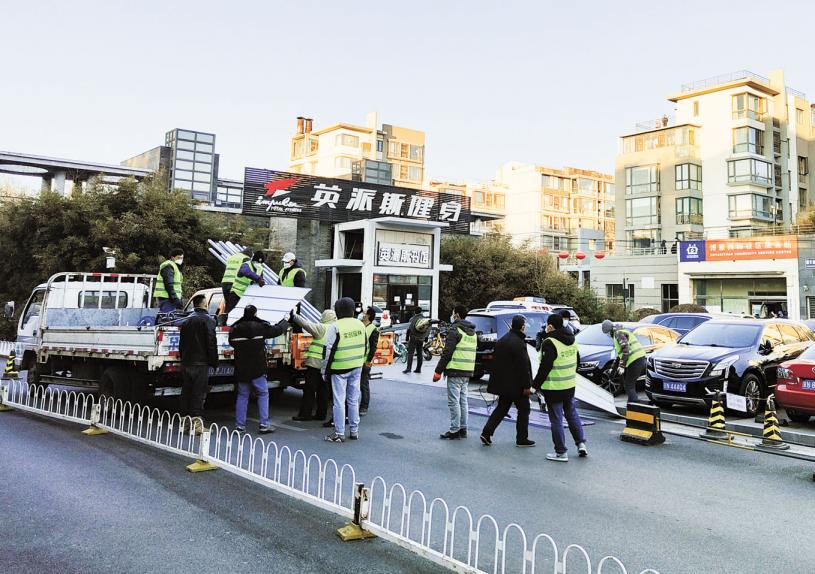在北京市海淀区，工作人员15日在阳性人员所住的小区门口搭建围挡。中新社