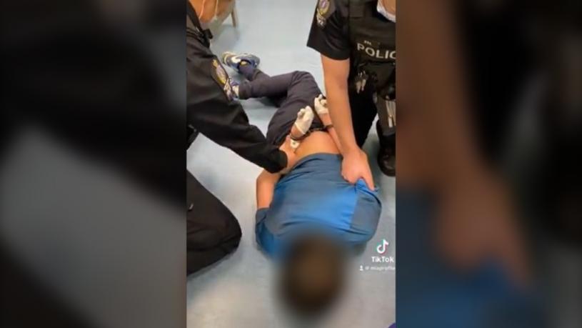 12歲的原住民兒童被警察戴上手銬，並制伏在地上。抖音圖