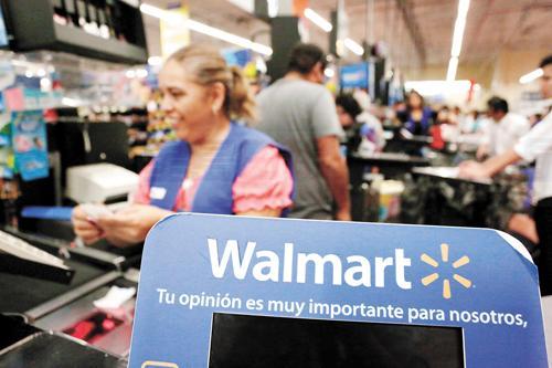 FILE PHOTO: A cashier smiles beyond a Walmart logo during the kick-off of the 'El Buen Fin' (The Good Weekend) holiday shopping season, at a Walmart store in Monterrey, Mexico, November 17, 2017.  The sign reads 