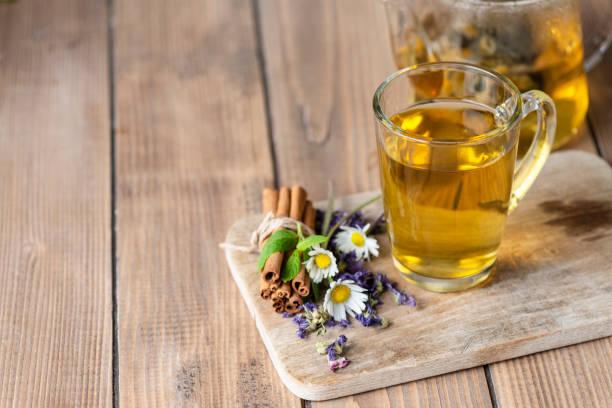 Herbal tea ingredients on wooden table with chamomile plants and cinnamon.