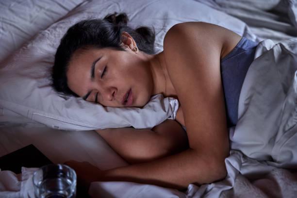 Hispanic young woman laying on bed with sore throat