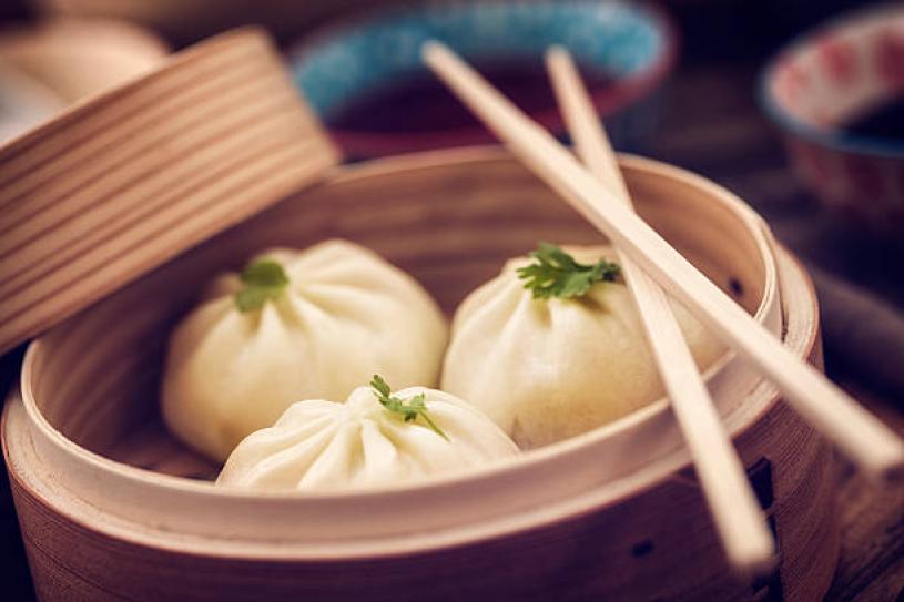 Traditional Dim Sum dumplings freshly steamed in a bamboo steamer. They can be filled with meat or veggies inside.