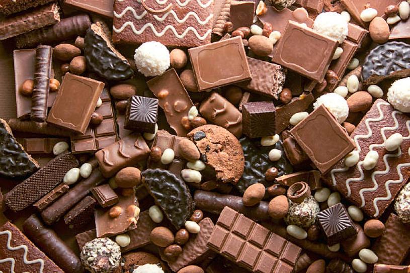 Chocolate background. Many pieces of chocolate, candies, cookies, biscuits, cakes and other sweets. Milk chocolate and dark chocolate. coconut candy