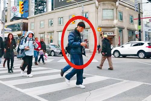 疑似华裔青年横过马路时只顾望着手机。 星报