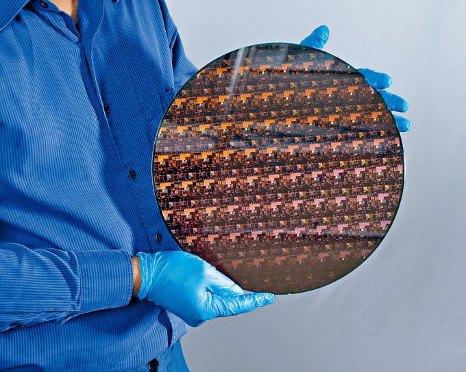 IBM人员展示一个晶体圆形片，包含用两纳米技术制成的芯片。