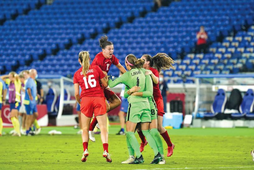 ■加拿大女足神奇队长辛克莱（左二）飞扑向拉贝在内的队友中，庆祝战胜瑞典队。
美联社