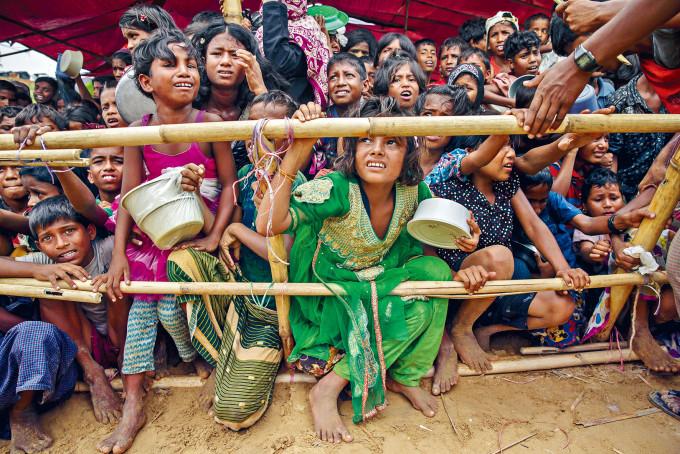 羅興亞孩童在孟加拉難民營等分發食物。
