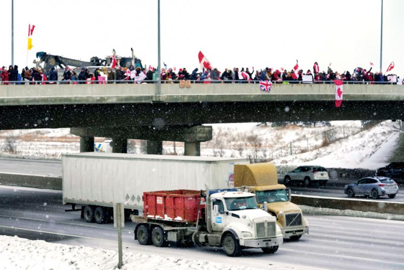■当卡车在多伦多400公路上行驶时，举著加拿大国旗的支持者站在天桥上欢呼。 加通社