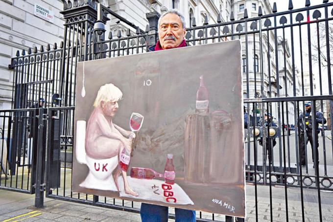 画家马尔周三在伦敦首相府外，展示讽刺约翰逊的漫画。