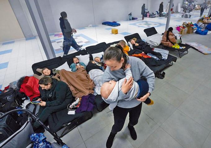在波兰一个由街市改建的临时收容中心，逃难的乌克兰妇女抱着她的婴儿。