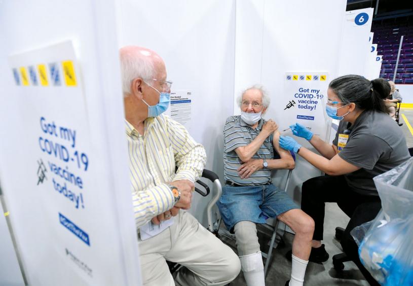 William Bechard, 83, left, watches his friend Rory O'Farrell, 92, left, receive his second dose of the COVID-19 vaccine at the 'hockey hub' mass vaccination facility at the CAA Centre during the COVID-19 pandemic in Brampton, Ont., on Friday, June 4, 2021. This NHL-sized hockey rink is one of CanadaÕs largest vaccination centres. THE CANADIAN PRESS/Nathan Denette