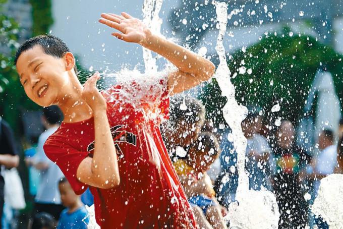 高溫天氣持續，江蘇南京的一個孩子在街頭噴泉處戲水。