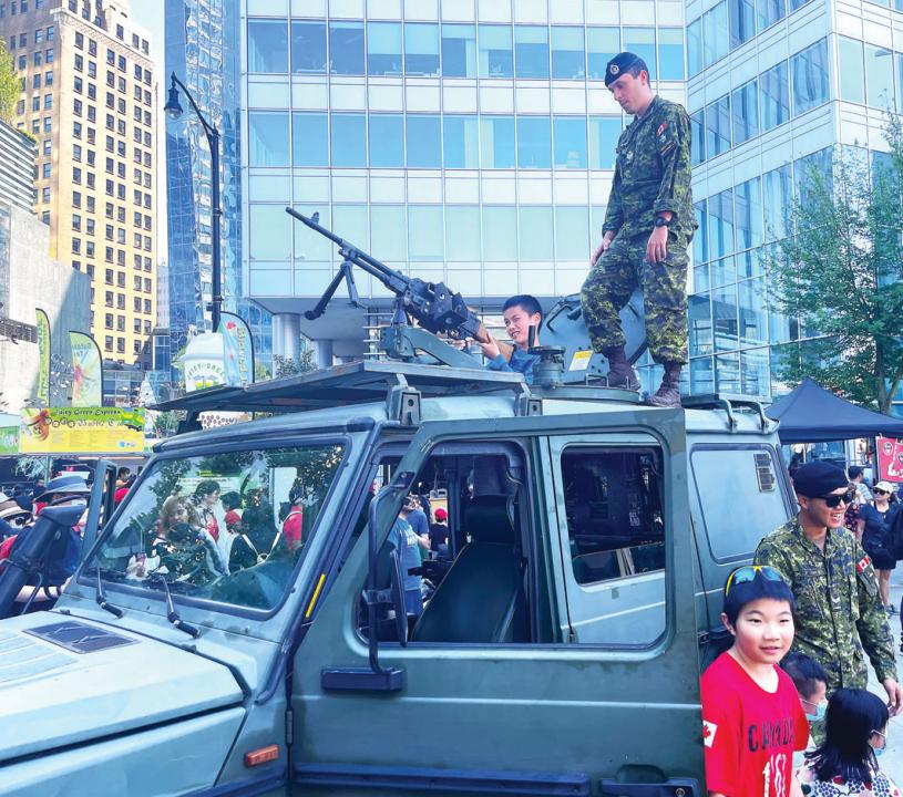 ■加軍協助小朋友登上裝甲車。