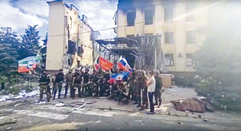 俄军与车臣士兵在乌克兰东部利西昌斯克市一座毁烂建筑物前，挥舞俄国和车臣共和国旗帜。美联社