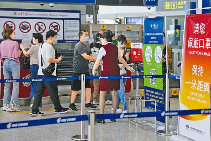 北京机场工作人员昨天引导旅客办理登机手续。