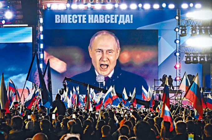 莫斯科红场周五举行庆祝乌克兰四地区并入俄国的音乐会，屏幕播出普京发表演说的画面。