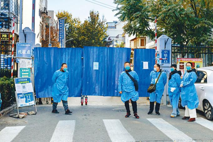 北京一個小區被封控，身穿防護服的人員在門外把守。
