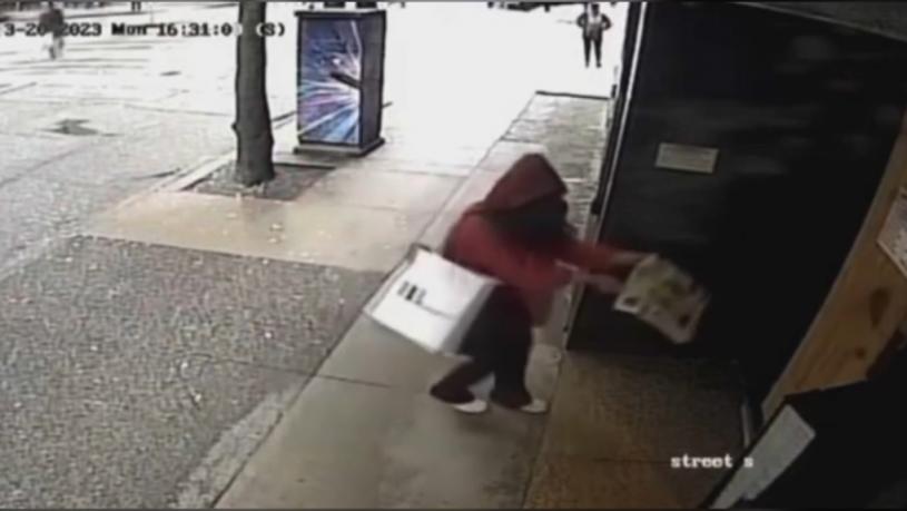 视频中可见，一名妇女拿着粪便向大厦大门扔去。CCTV截图