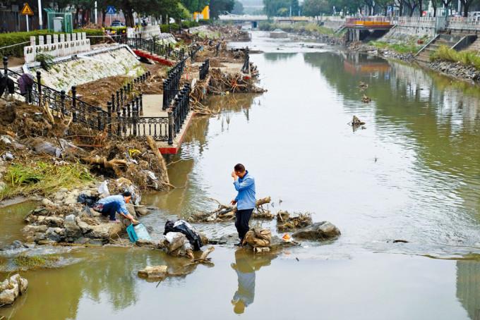 北京門頭溝區受災嚴重，居民在河道內收拾雜物。
