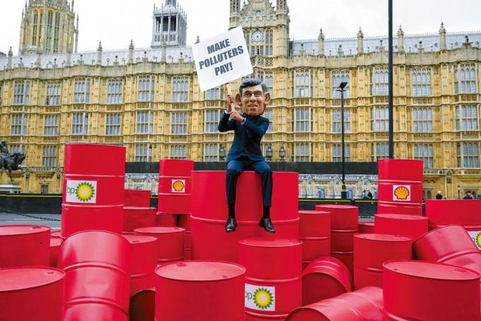 在聯合國「氣候雄心」峰會前夕，樂施會成員戴起辛偉誠面具，周二在倫敦國會外示威，呼籲英國的石油公司繳納更多稅款。
